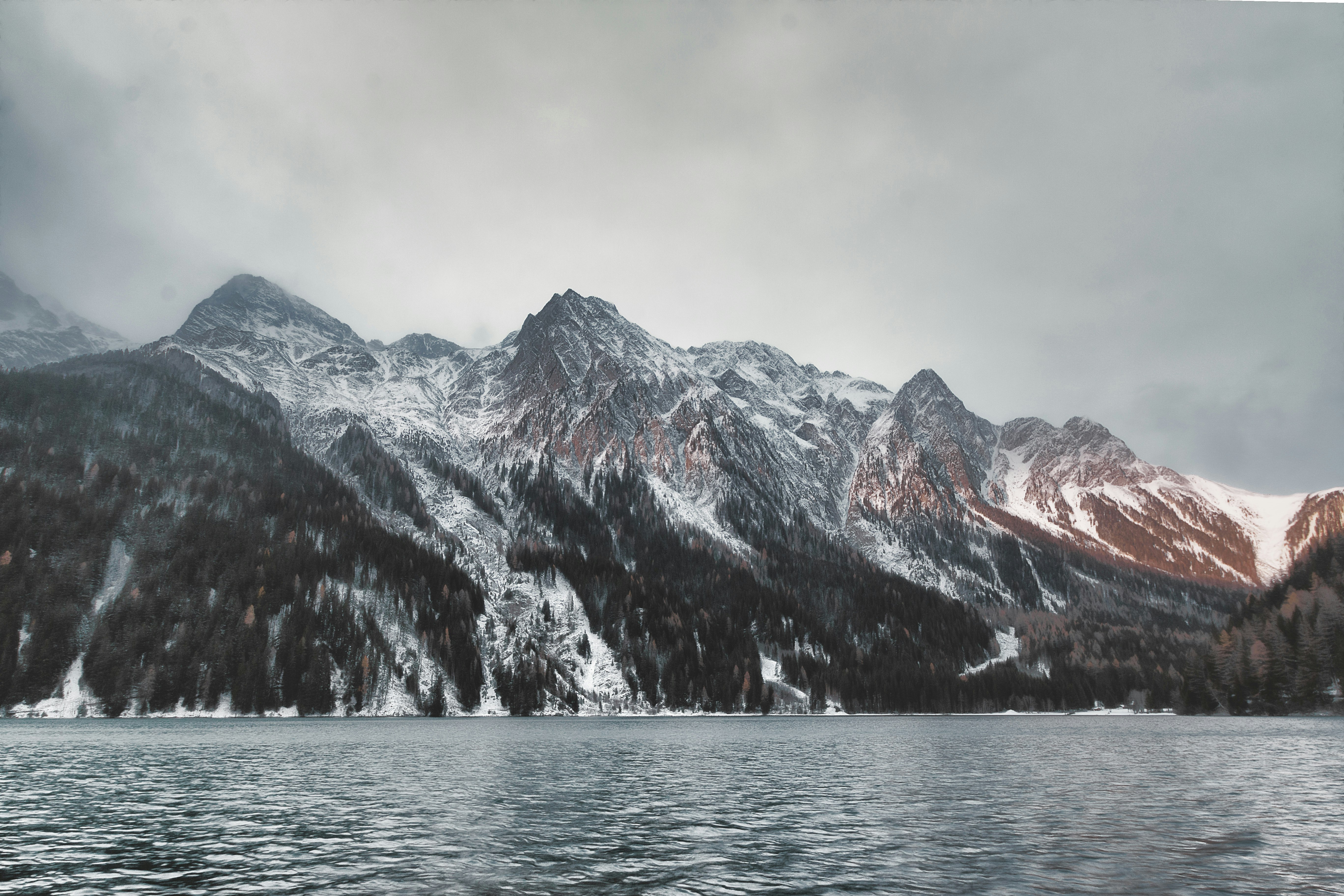 mountain covered with snow under gray clouds